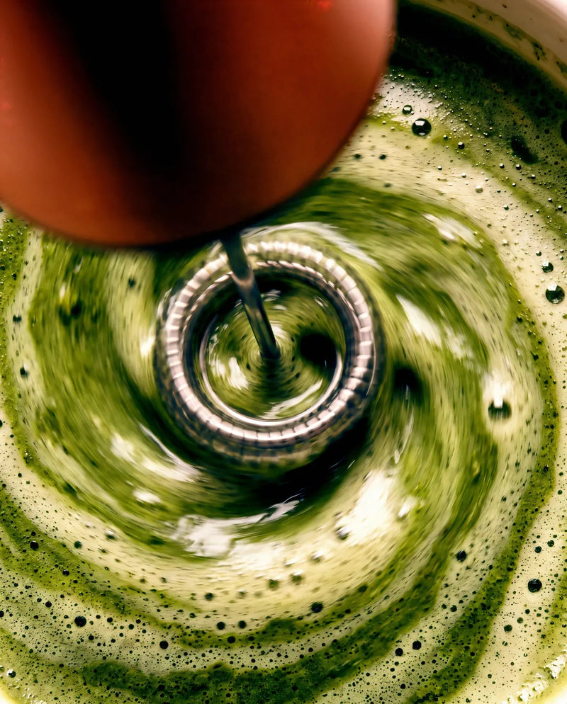 The copper frother spinning the latte, close up