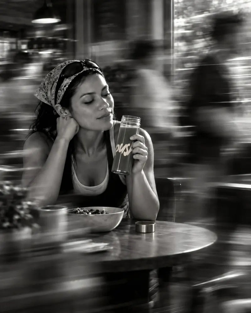 A woman at a café window with the Push tumbler while the street blurs past