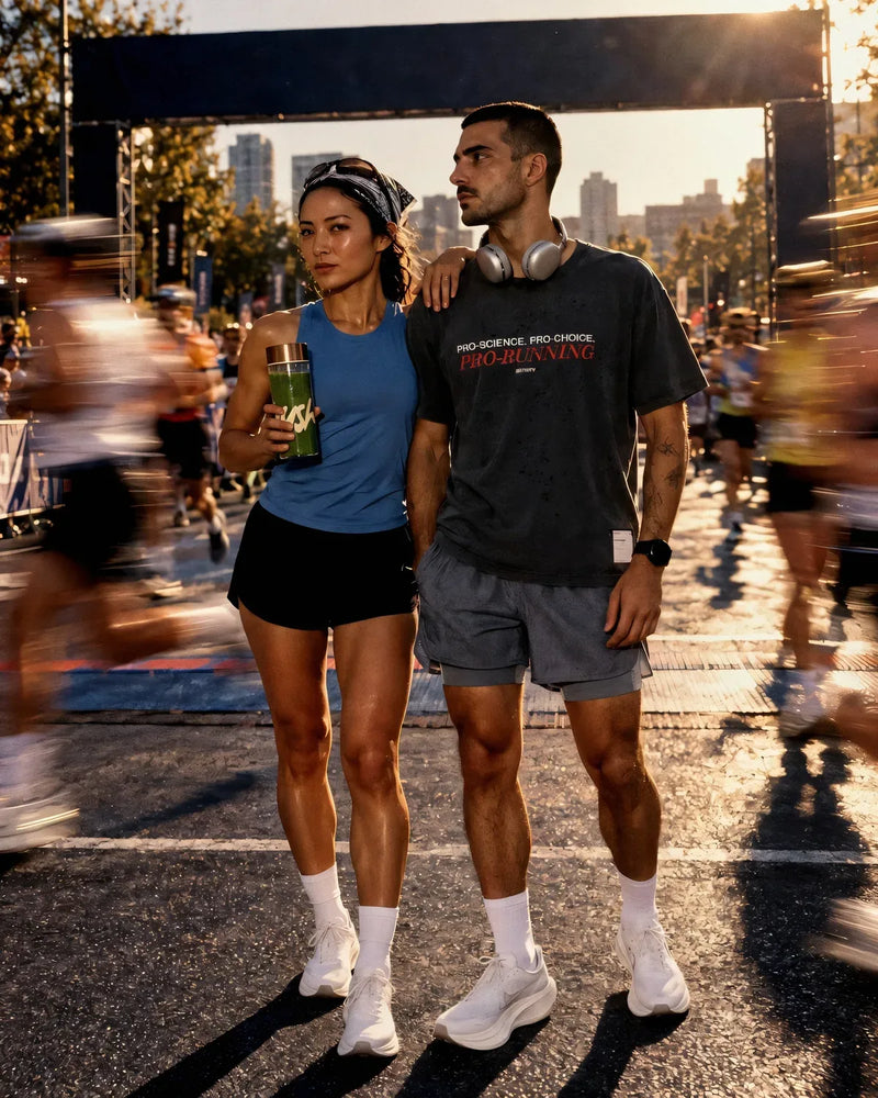 Two runners stand at a race finish as the field streaks past